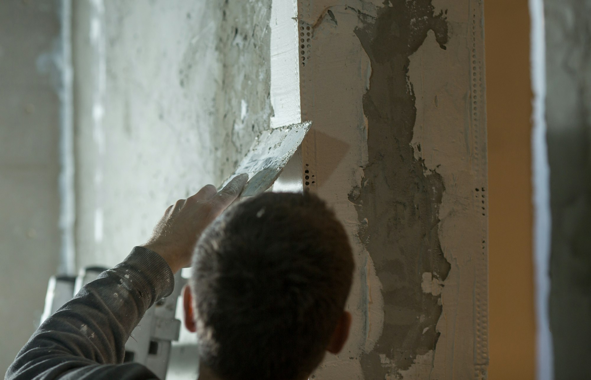 a male plasterer plasters a wall with a spatula.