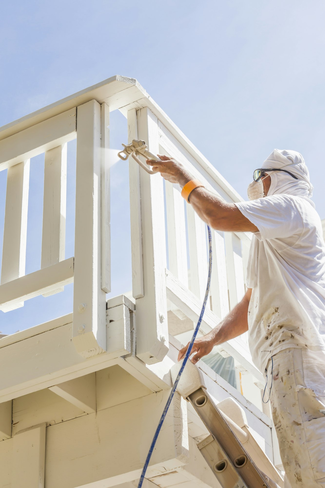 House Painter Spray Painting A Deck of A Home